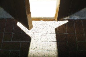 Stock photo of a wooden door that is slightly open and allowing light to flood in