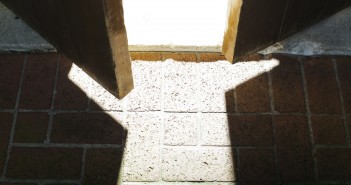 Stock photo of a wooden door that is slightly open and allowing light to flood in