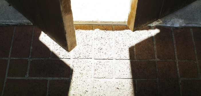 Stock photo of a wooden door that is slightly open and allowing light to flood in