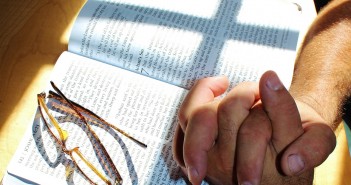 Stock art of someone with their hands clasped on an open bible