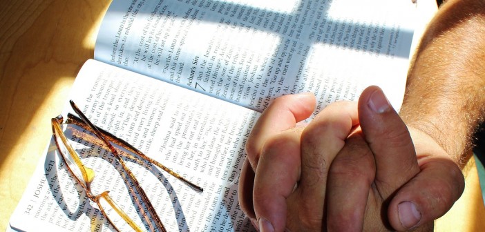 Stock art of someone with their hands clasped on an open bible