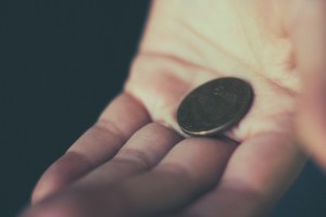 Stock photo of a white hand holding a single coin