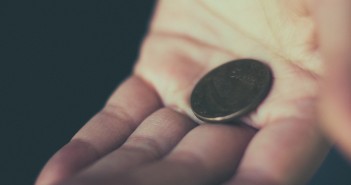Stock photo of a white hand holding a single coin