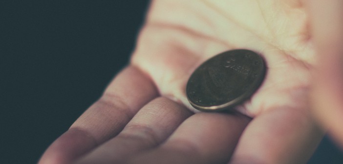 Stock photo of a white hand holding a single coin