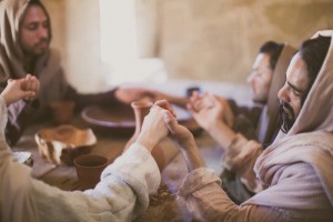 Stock photo of a group of Middle Eastern men holding hands and praying around a table