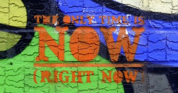 Stock photo of graffiti on a concrete wall that reads "the only time is NOW (right now)