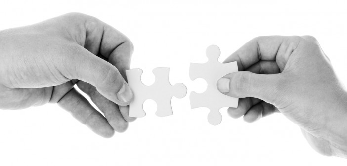 Black and white stock photo of two individuals putting two puzzle pieces together