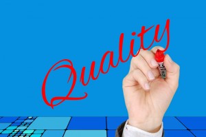 Stock photo of a hand writing "Quality" in a cursive script