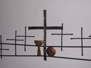 Stock photo of six black, hammered metal crosses with a gold hammered chalice and a copper hammered communion plate