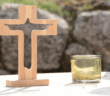 Wooden cross and a candle atop a table