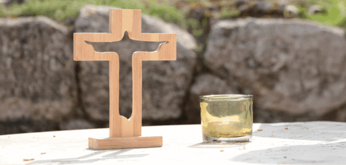Wooden cross and a candle atop a table