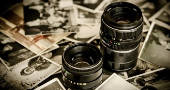 Stock photo of two DSLR camera lenses among a pile of black-and-white photos