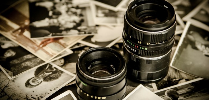 Stock photo of two DSLR camera lenses among a pile of black-and-white photos