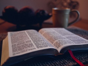 Stock photo of an open bible on a table with a coffee mug in the background