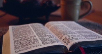 Stock photo of an open bible on a table with a coffee mug in the background