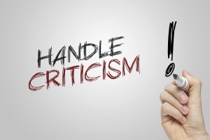Stock photo of a hand writing "HANDLE CRITICISM!" on a whiteboard