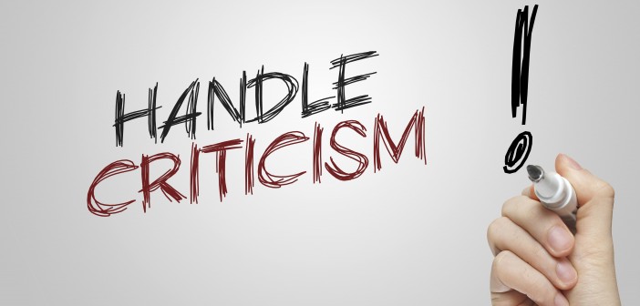 Stock photo of a hand writing "HANDLE CRITICISM!" on a whiteboard