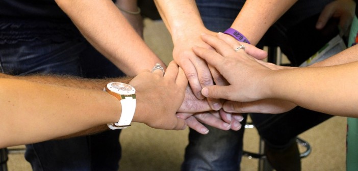 Stock art of a group of hands in the middle of a huddle