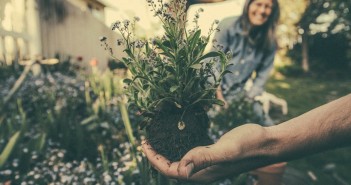 Stock photo of a gardener unearthing a flower with a smiling woman in the background