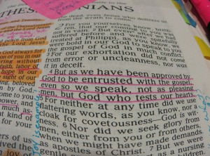 Stock photo of a heavily annotated and highlighted bible opened up to 1 Thessalonians with chapter 2, verse 4 underlined in pink