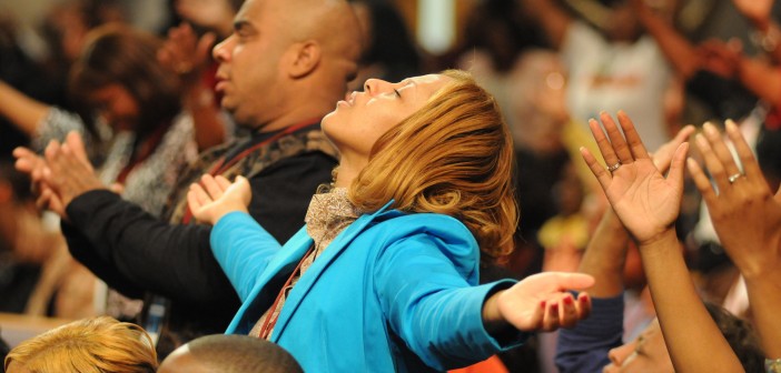 Stock photo of a large, diverse group of people in worship with their arms outstretched