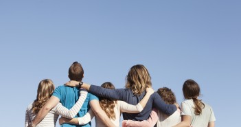 Stock photo of the backs of a white family - mom, dad, and four daughters - looking up at the sky
