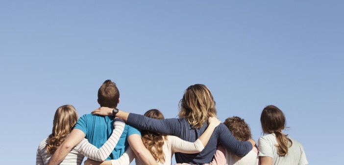 Stock photo of the backs of a white family - mom, dad, and four daughters - looking up at the sky