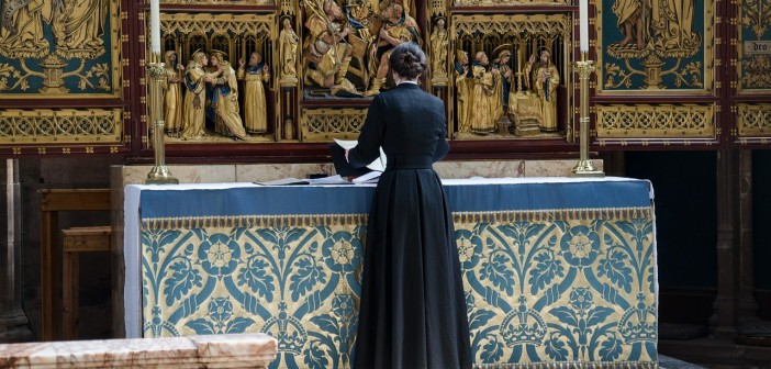 Stock photo of a clergywoman at an altar preparing for services