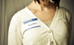 Stock photo of a white woman wearing a nametag that reads "hello my name is VISITOR"
