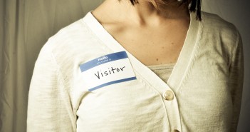Stock photo of a white woman wearing a nametag that reads "hello my name is VISITOR"