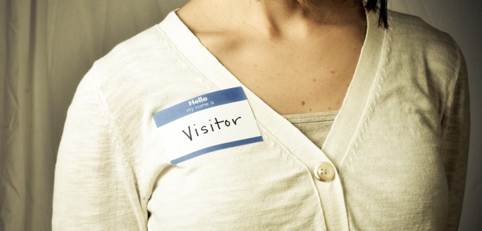 Stock photo of a white woman wearing a nametag that reads "hello my name is VISITOR"