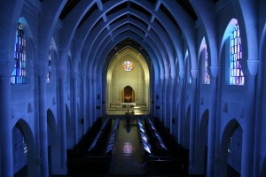 Stock photo of the interior of an empty sanctuary with the lights turned off and sunlight pouring in through the stained-glass windows