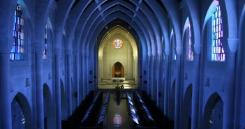 Stock photo of the interior of an empty sanctuary with the lights turned off and sunlight pouring in through the stained-glass windows