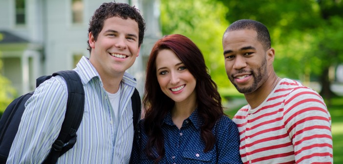 Stock photo of three young individuals - a white man, a white woman, and an African American man - posing for a portrait outside of a house