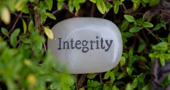 Stock photo of a stone with the word "Integrity" engraved on it in a bush