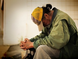 Stock photo of a grungy, tattooed white man who is praying