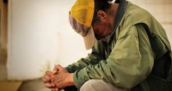 Stock photo of a grungy, tattooed white man who is praying