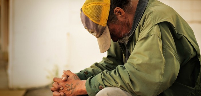 Stock photo of a grungy, tattooed white man who is praying