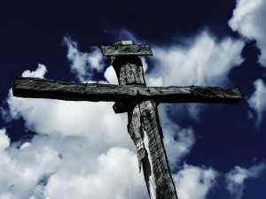 Stock photo of a cross against a blue sky with some white fluffy clouds