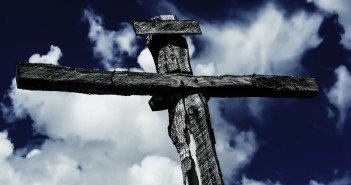 Stock photo of a cross against a blue sky with some white fluffy clouds