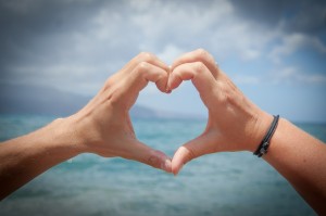 Stock photo of a pair of hands forming a heart looking out over a body of water