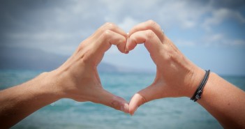 Stock photo of a pair of hands forming a heart looking out over a body of water