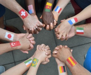 Stock photo of a diverse group of interlocked hands with different flags painted on their wrists