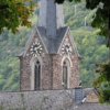 Stock photo of a steeple/bell tower with a clock on it in the mountains. It is approximately 4:10 in the afternoon.