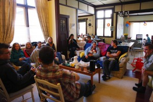 Stock photo of a group of mixed-age white people sitting in a living room in a circle engaging in some of fellowship