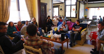 Stock photo of a group of mixed-age white people sitting in a living room in a circle engaging in some of fellowship