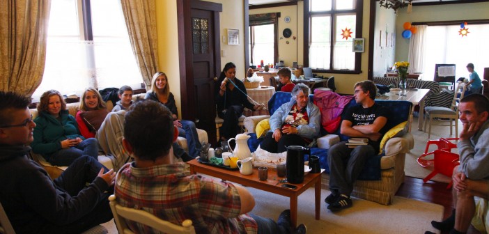 Stock photo of a group of mixed-age white people sitting in a living room in a circle engaging in some of fellowship
