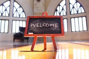 Stock photo of a small chalkboard in the middle of a room that has "WELCOME" written on it