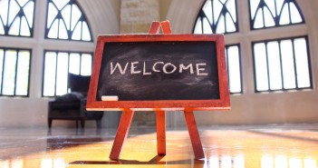 Stock photo of a small chalkboard in the middle of a room that has "WELCOME" written on it