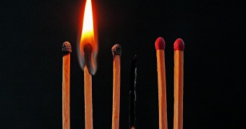 Stock photo of seven matches: two that have not been lit ever, one that is currently lit, two that have been lit but are now extinguished, and one that is completely burnt out